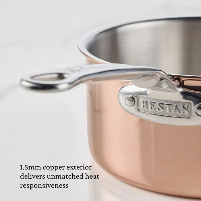 Close-up of a professional-grade copper pan, specifically the Polished Copper 0.75-Quart Butter Warmer with a stainless steel handle, branded CopperBond Aura™. Text reads: 1.5mm copper exterior delivers unmatched heat responsiveness. The background is plain white—showcasing the excellence of premium copper cookware.