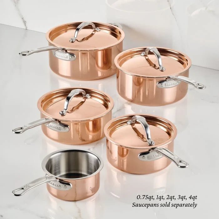 Five pieces of CopperBond Aura™ professional-grade copper cookware with metal handles and lids are arranged on a marble surface. One saucepan reveals a stainless steel interior. The collection includes sizes from 0.75 qt to 4 qt, featuring the Polished Copper 0.75-Quart Butter Warmer, ideal for preparing delicate sauces. Text notes that saucepans are sold separately.