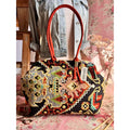 Atenti Sew Crewel Molly handbag with multicolor crewel-style embroidery, bright red double handles, and structured snap-frame silhouette
