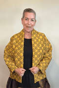 Model wearing the Kozan Sia open-front jacket with an allover mustard and olive puzzle-piece print, shown from front and back.